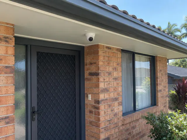 Exterior brick house entry with dome CCTV camera mounted under the eave in Reedy Creek