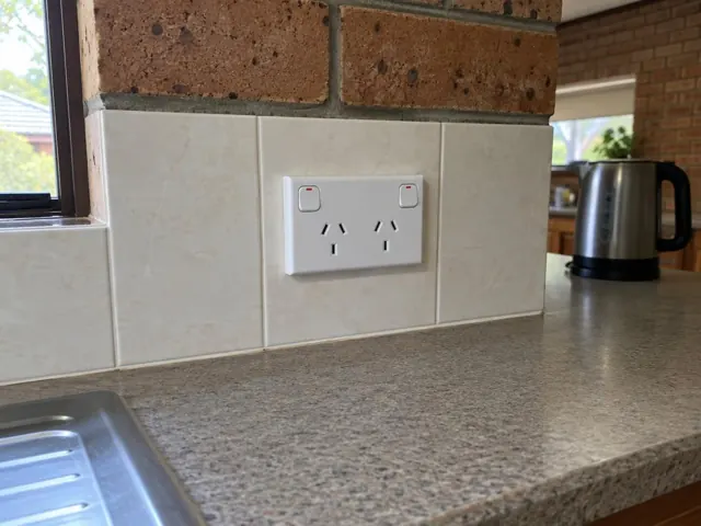 Double power point on a tiled kitchen backsplash above a benchtop in Robina